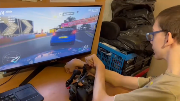 Levis, a co-designer with cerebral palsy, is playing the racing game Forza with a customized Xbox controller.