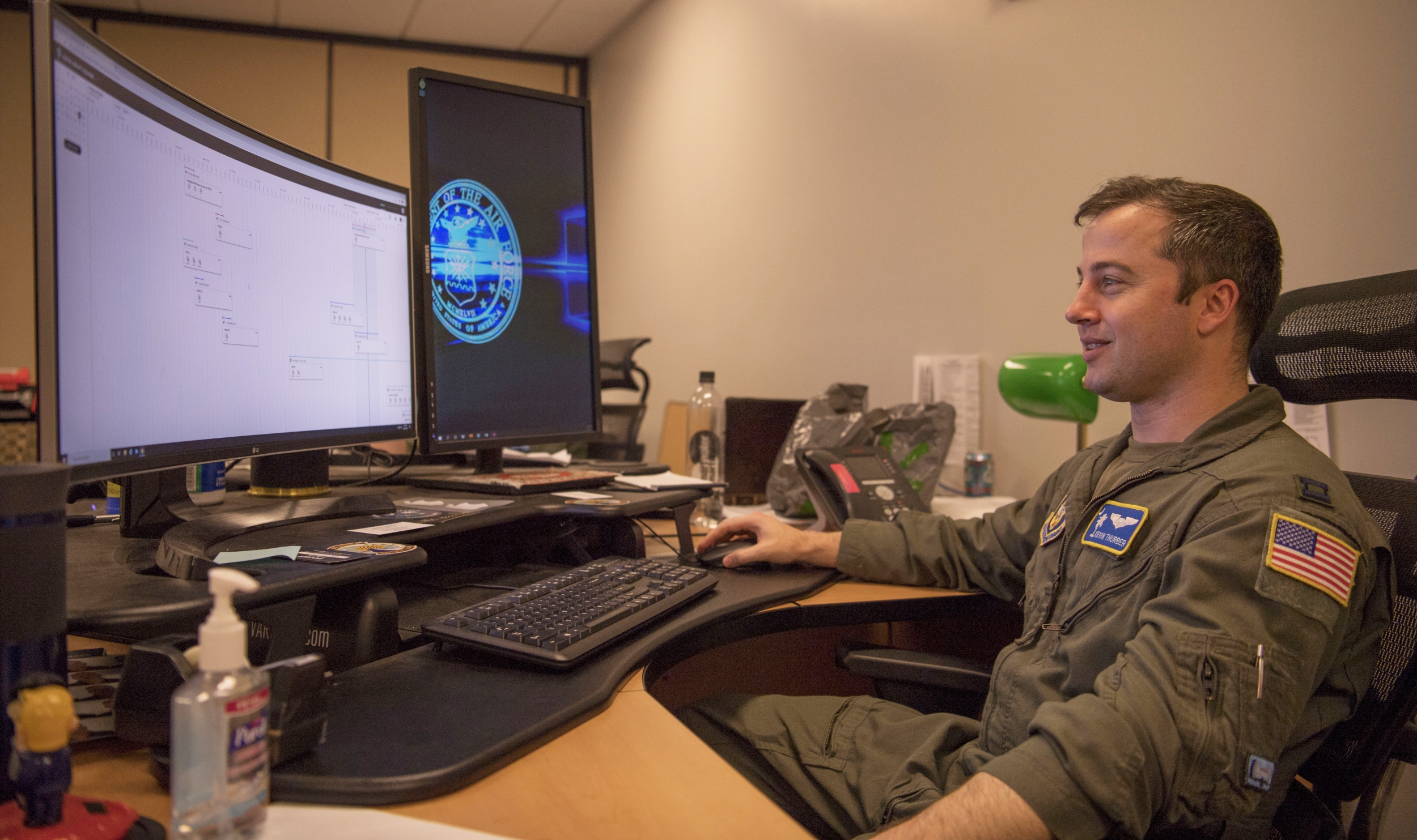 An airman sits at a desk, using a program on a computer screen. 