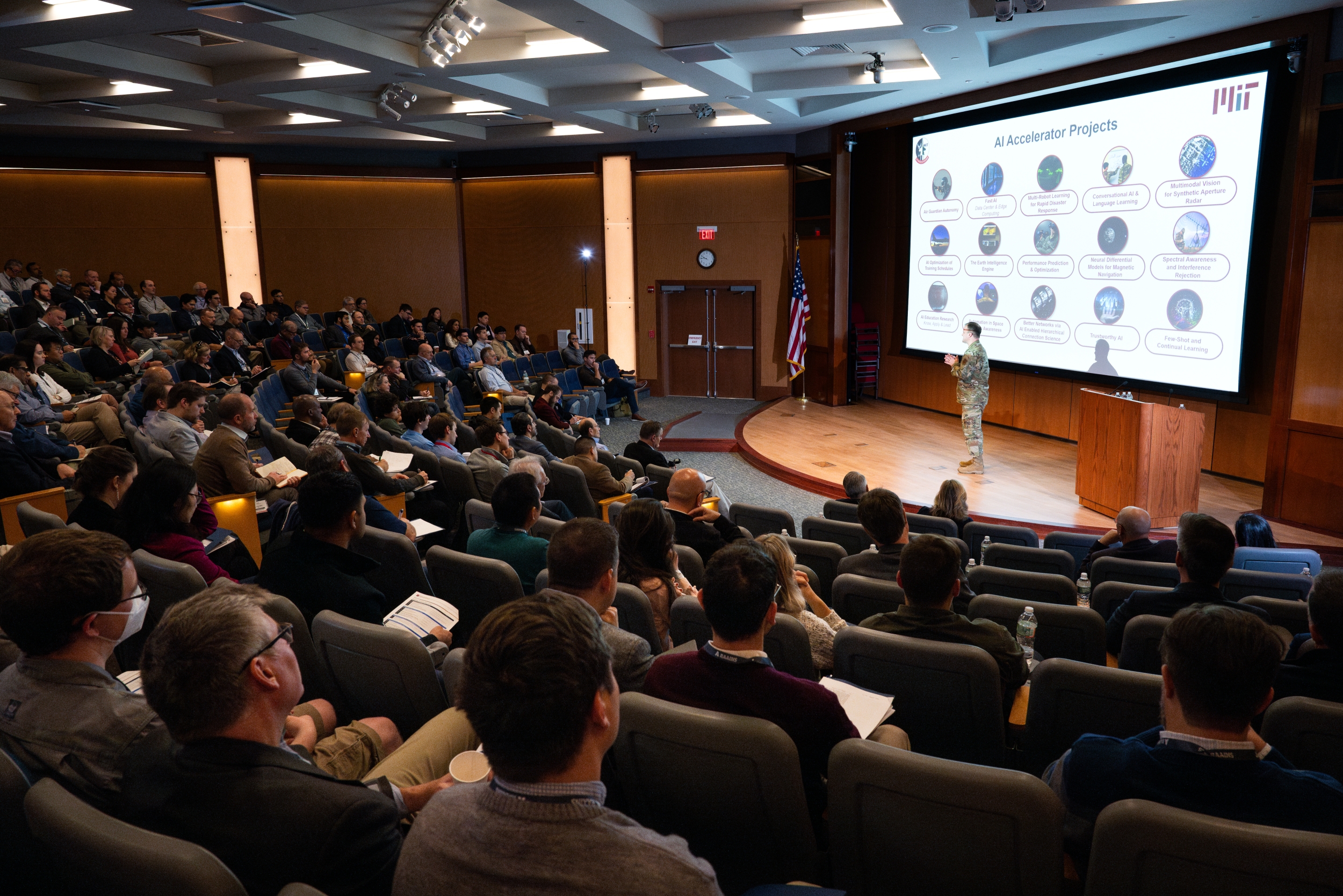 a colonel gives a keynote address on staff in an auditorium of onlookers. 