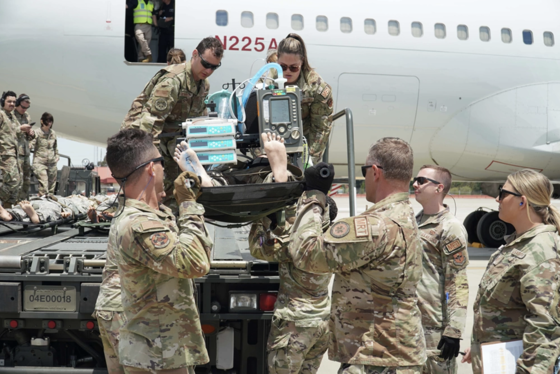 A group of airmen practice lifting a patient off a vehicle.