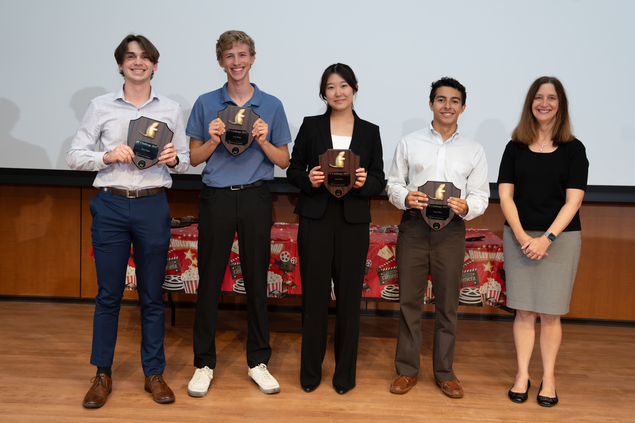 The four interns from the winning team hold their awards for a photo. They are standing in a line together with Director Melissa Choi.