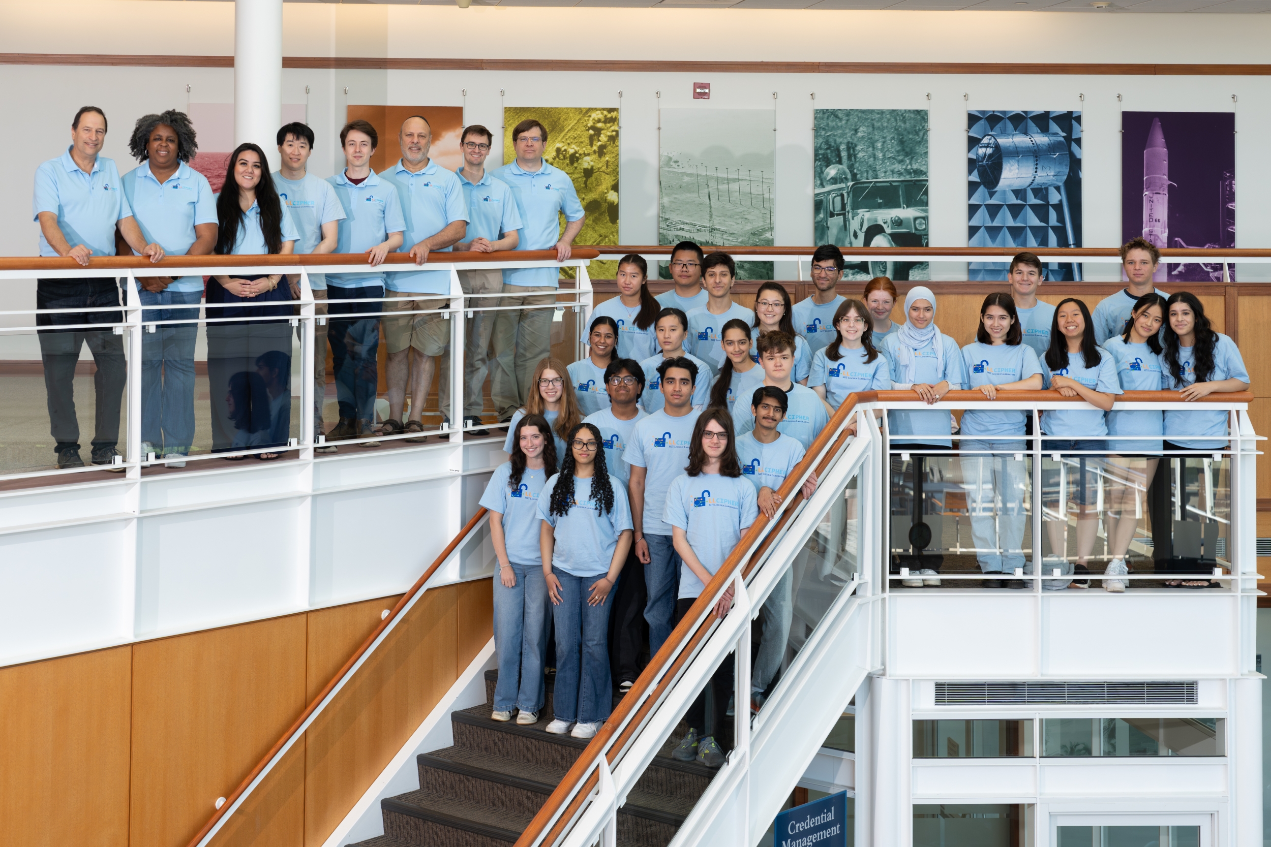 The full 2025 LLCipher student class is gathered for a group photo in the Wood Street lobby on a staircase.