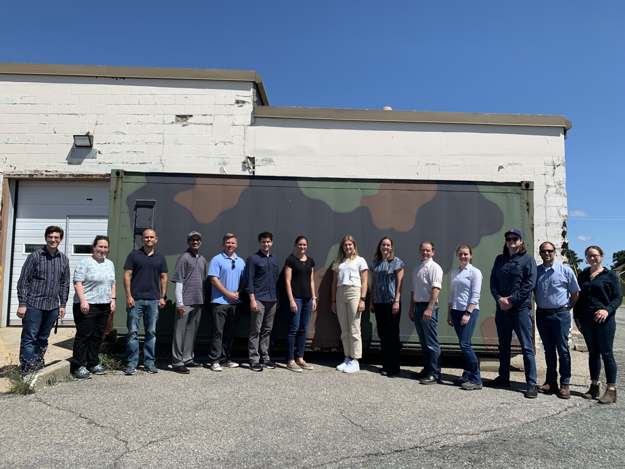 A team of researchers pose for a group photo outside of a building on the Joint Base Cape Cod.