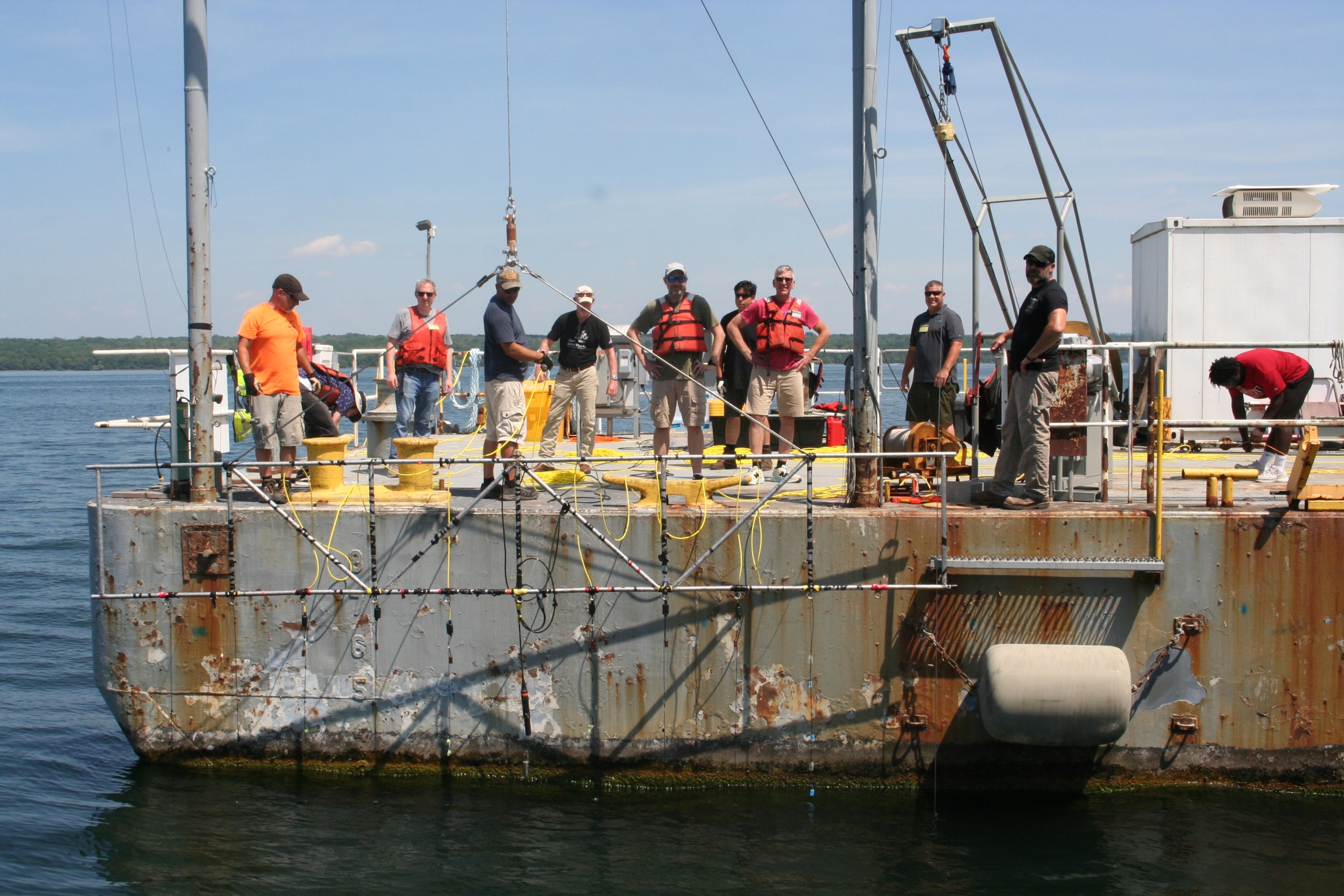 A group of researchers lowering equipment into the ocean from a boat. 