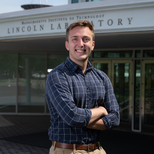 A portrait photograph of Joseph Rottner outside the front entrance of MIT Lincoln Laboratory.