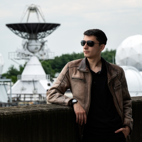 Photo of Madison Lagos standing outside with a large radar in the background. 