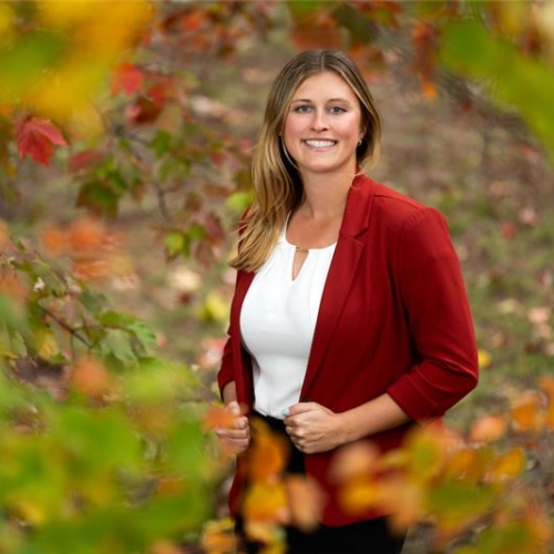 A photo of Jordan Wynn with fall trees in the foreground.