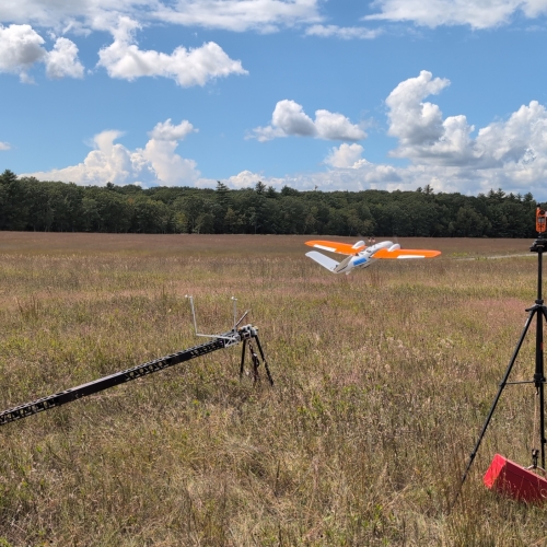 The research team's data collection drone is being launched from a ramp in a field on a clear day. 
