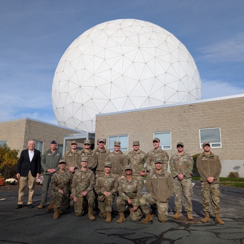 14 Air Force ROTC cadets pose for a photo in front of the HUSIR radar antenna radome. 
