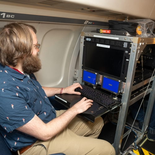 A man types on a keyboard onboard an aircraft.