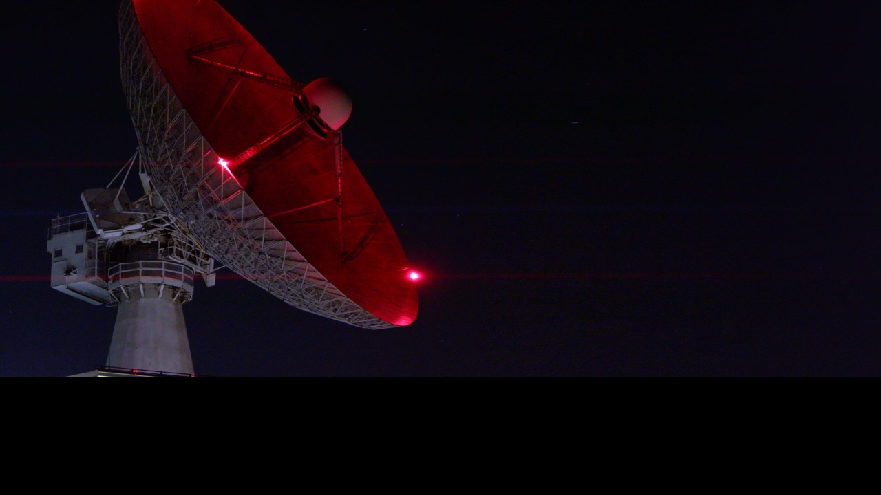 A satellite with red lights points towards the sky