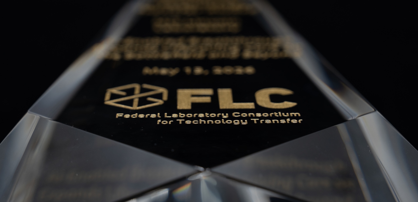 A glass award with the Federal Lab Consortium logo etched on the front.