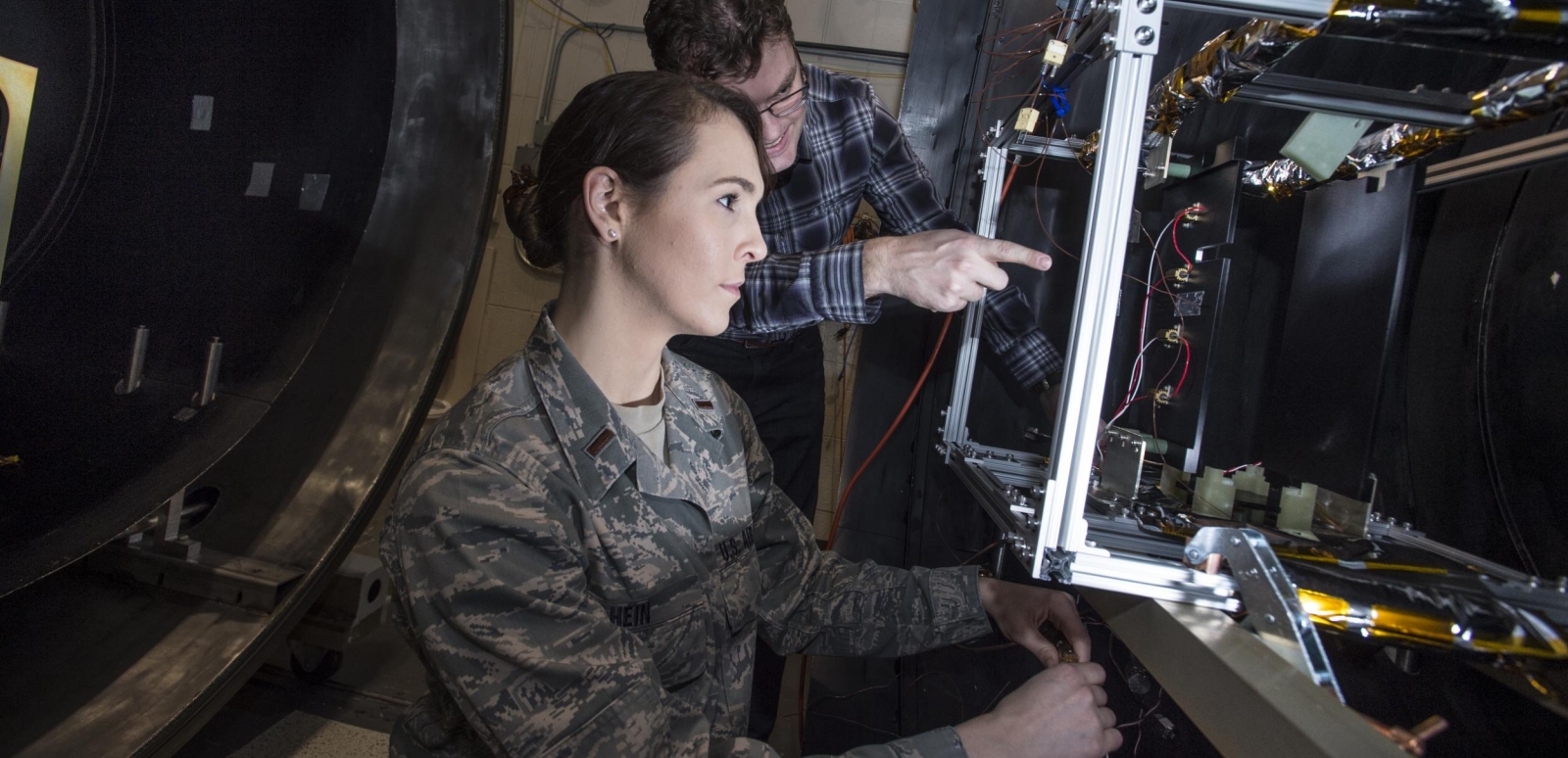 Military Fellow Ayesha Hein works on a satellite in the environmental test facility. 