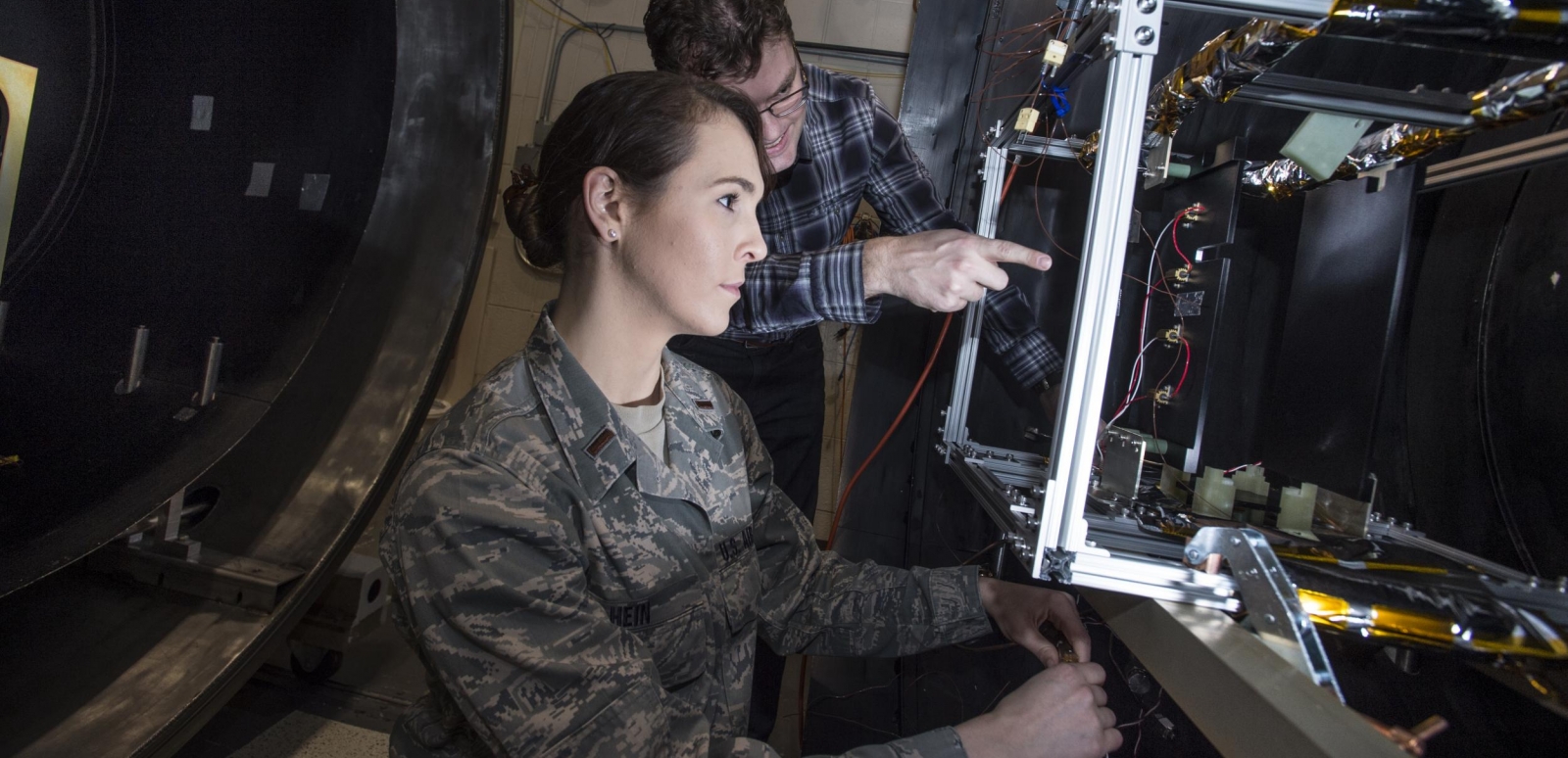 Military Fellow Ayesha Hein works on a satellite in the environmental test facility.