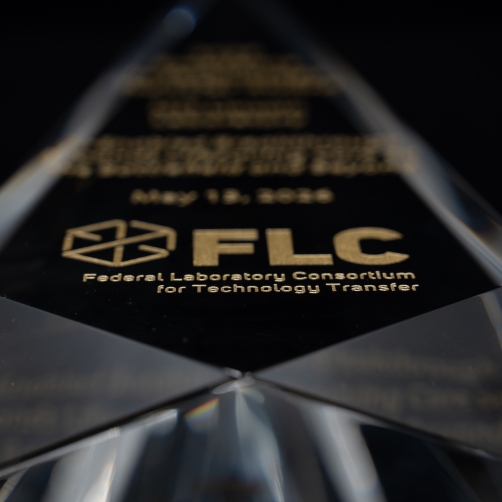 A glass award with the Federal Lab Consortium logo etched on the front.