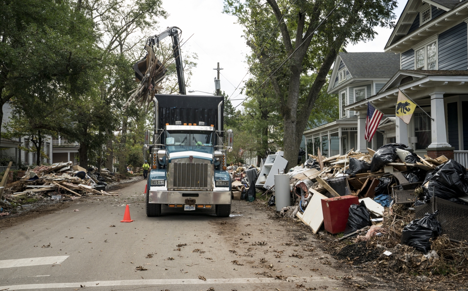 A photo of a large truck picking up debris lining a street