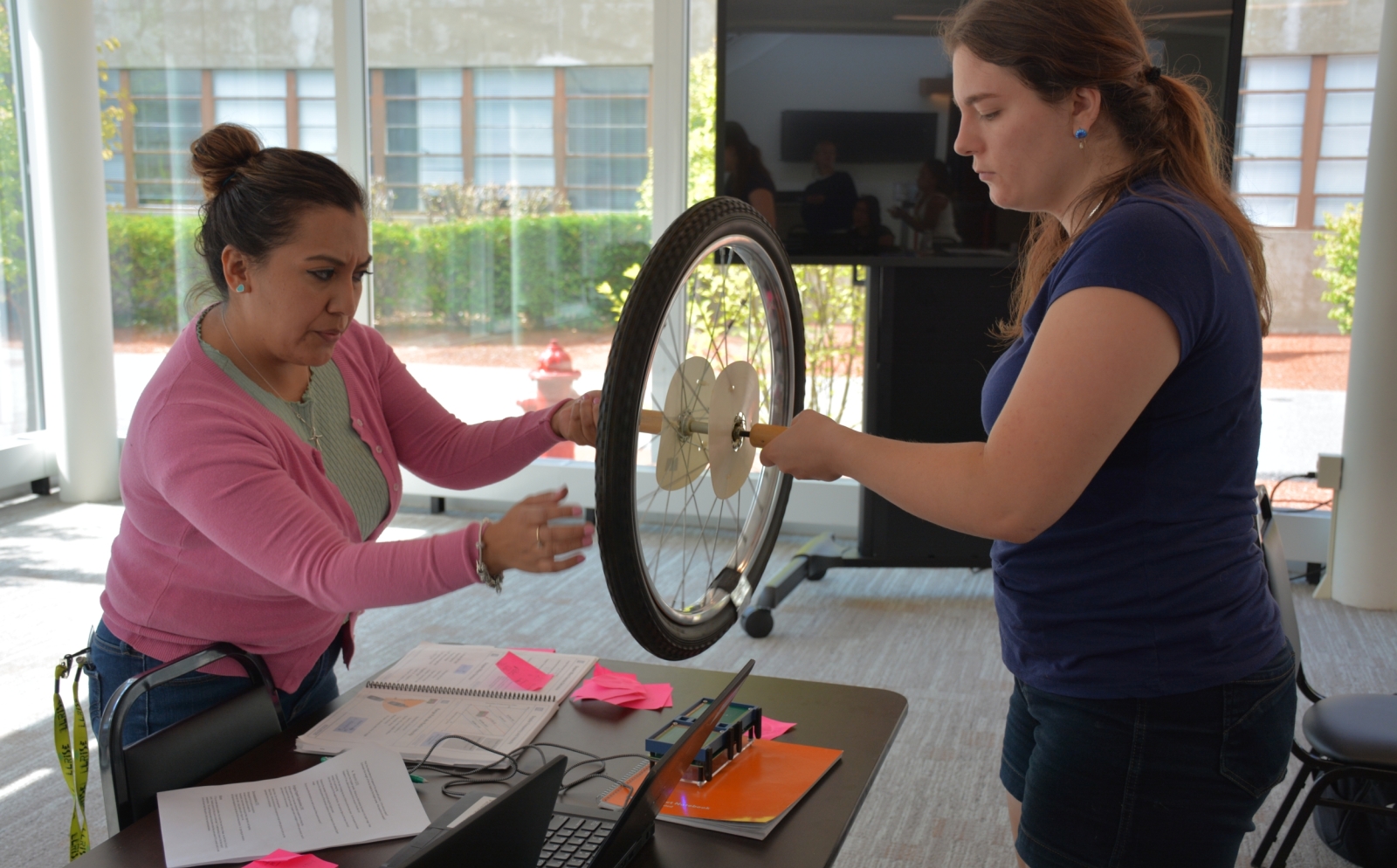 A photo of Esmeralda Hernandez and Liz Raine spinning a wheel above a small radar system they built.