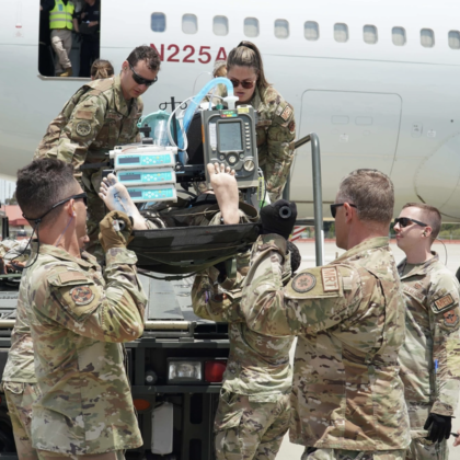 A group of airmen practice lifting a patient off a vehicle.