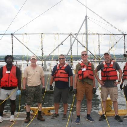 A group of researchers smile on a boat for a group photo. 