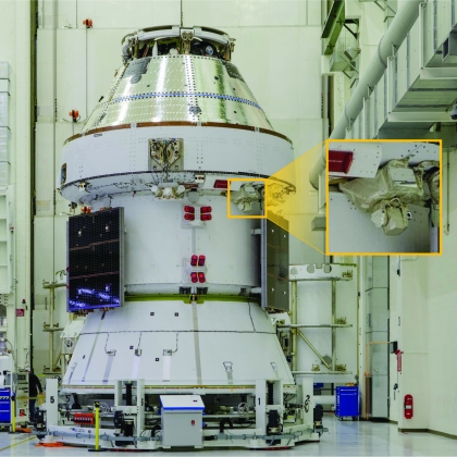 A spacecraft sits inside Kennedy Space Center. A callout box outlines where a laser communications terminal is located on the spacecraft.