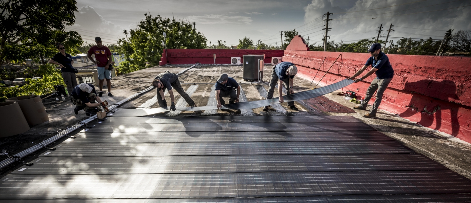 All hands are on deck as the team adheres the solar modules onto the roof of the Boys and Girls Club. Photo: Lorenzo Moscia