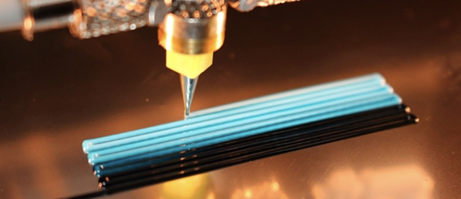 a photo of a 3d printer nozzle extriding material onto a piece of glass.
