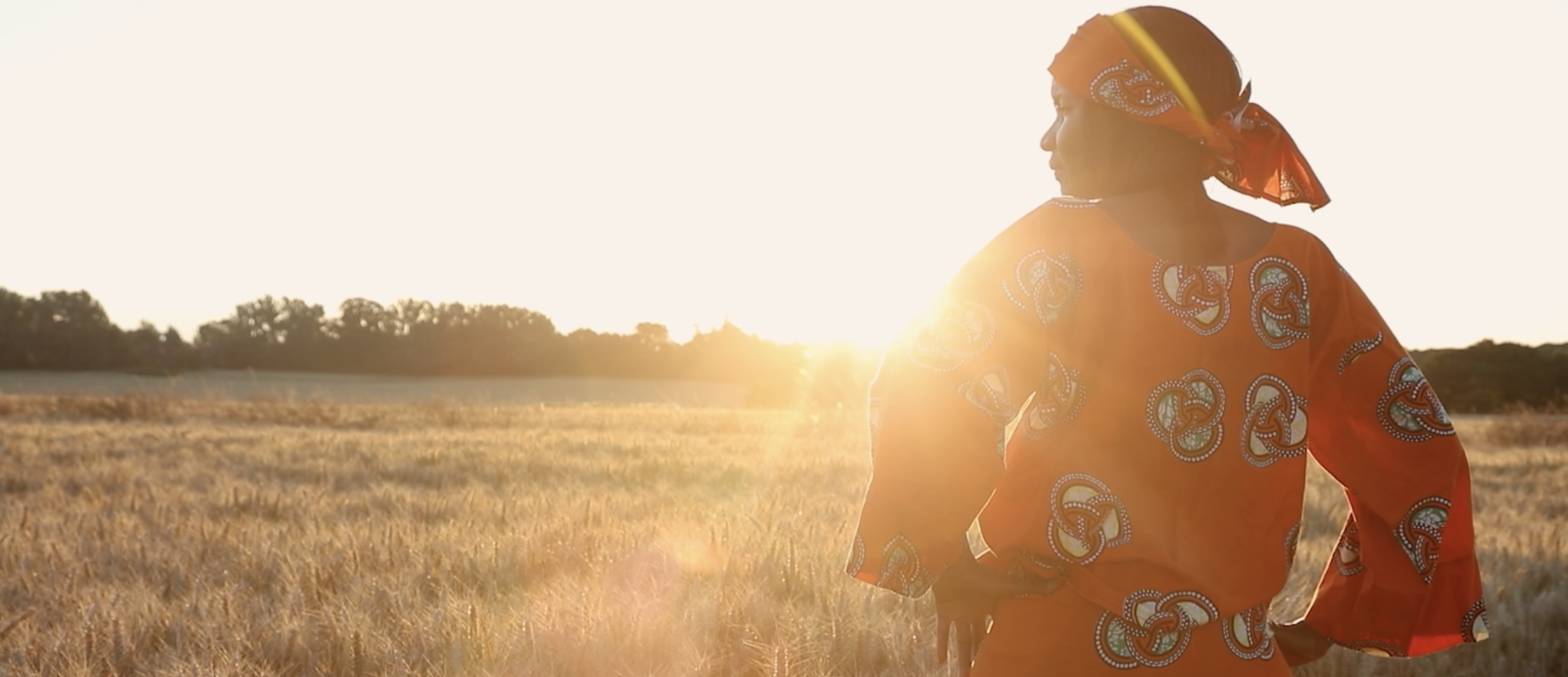 A photo of a woman with her hands on her hips, standing in a field.