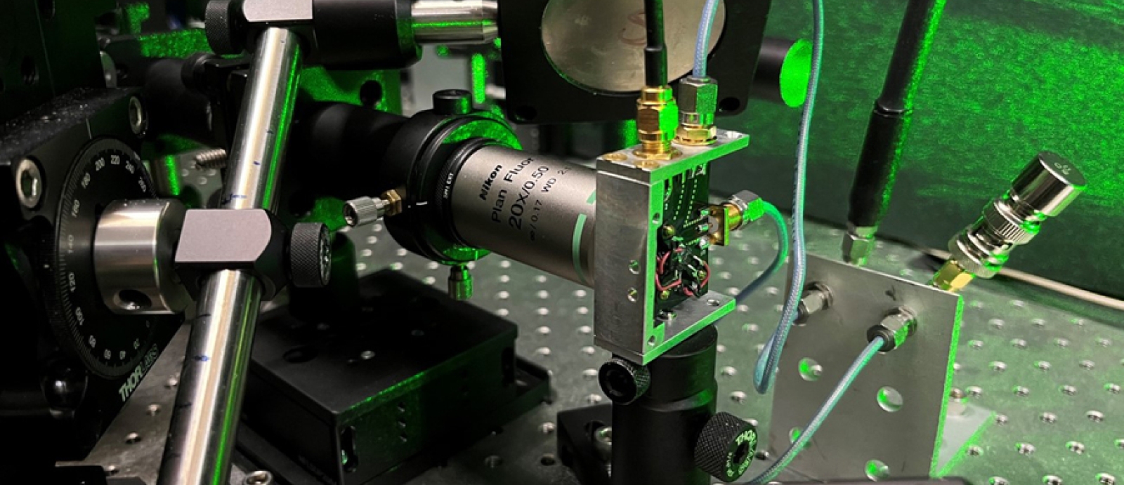 Hardware set up on a lab bench, with green laser light illuminating the background.