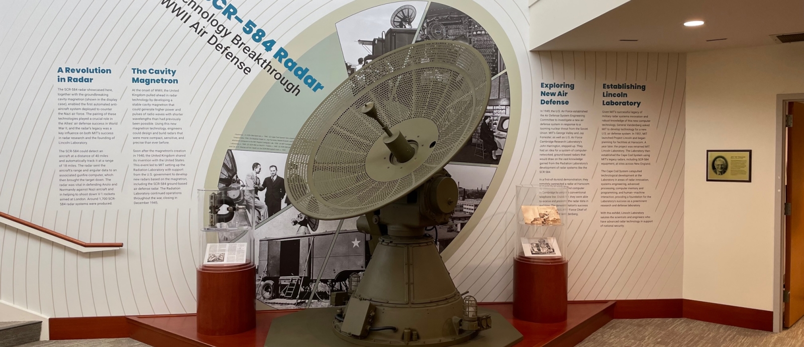 A photograph of the SCR-584 radar at Lincoln Laboratory in front of a wall of text about its development and use in World War II.