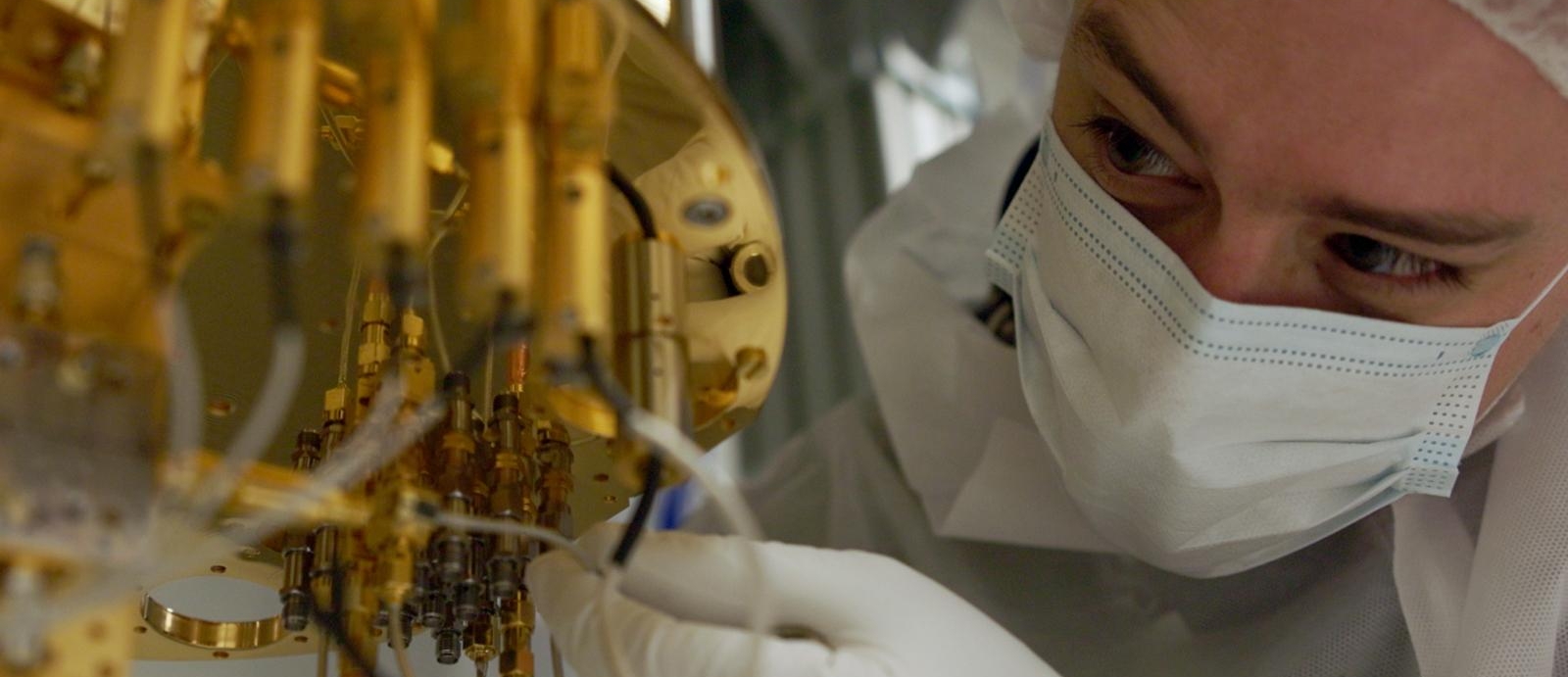 A researcher makes adjustments to a dilution refrigerator, a large piece of hardware for cooling quantum systems.