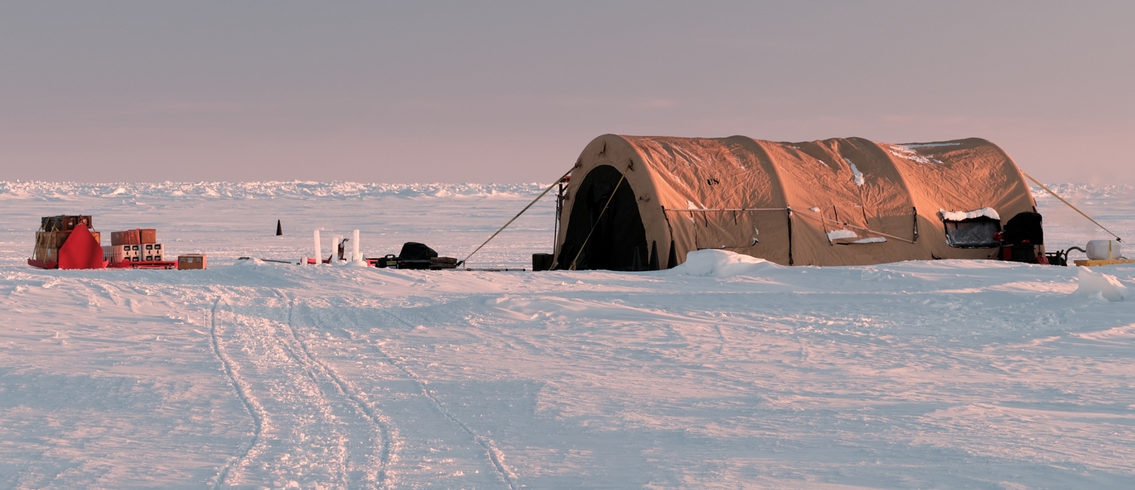 A large tent and supplies sit atop ice in the Arctic. 