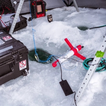 Research equipment is laid out on a sheet of ice with a hole. 