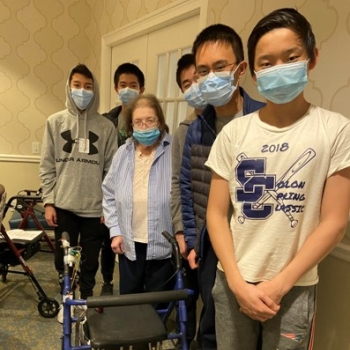 The MassBuilders student team and their co-designer Caroline pose for a photo together with the rollator walker that they modified for the challenge. 