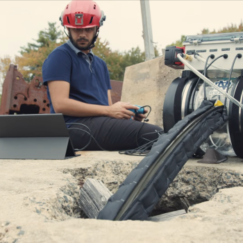 Photo shows a technician using a vine robot to surveill an underground space.