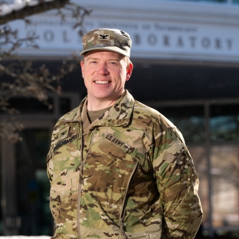 Military fellow Ian Fleischmann smiles for a photo in front of Lincoln Laboratory’s main entrance.