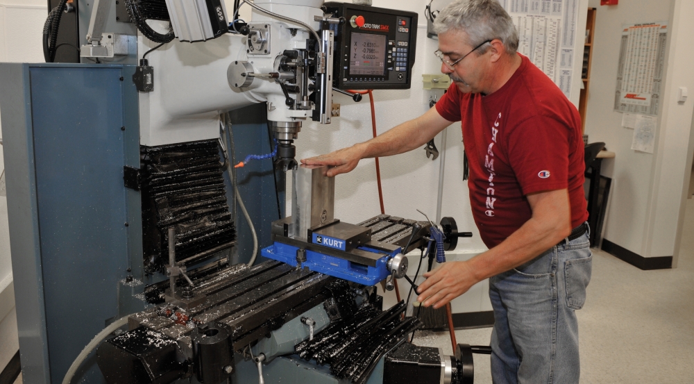 A machinist sets up new billet of aluminum to be machined into a complex part for an aircraft pod program.