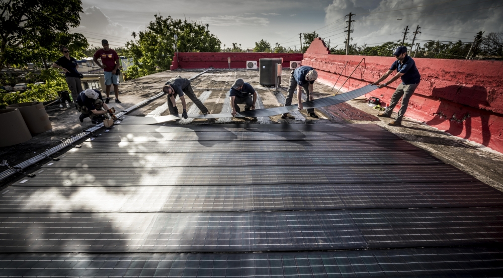 All hands are on deck as the team adheres the solar modules onto the roof of the Boys and Girls Club. Photo: Lorenzo Moscia