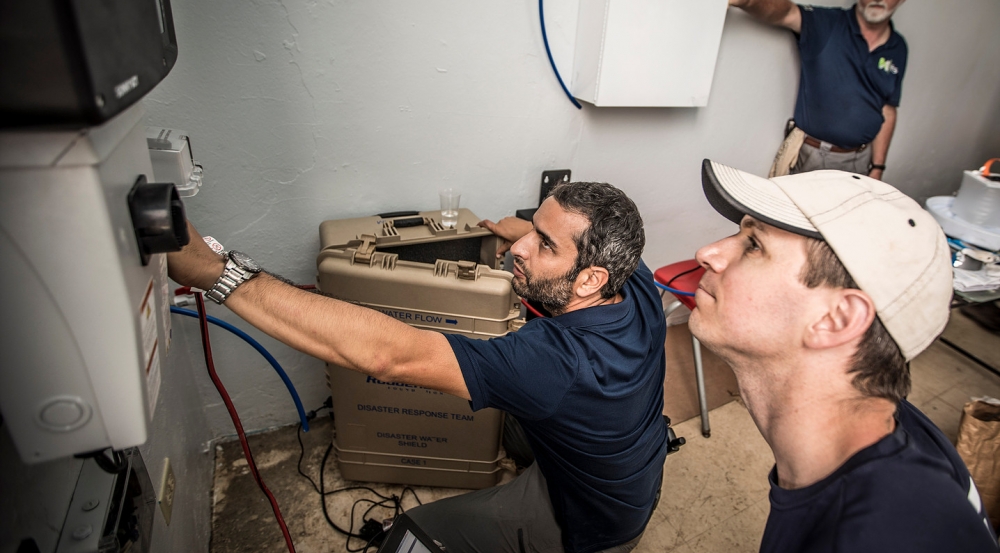 Erik Limpaecher, right, leader of the Lincoln Laboratory Energy Systems Group, and Alex Hatoum, left, IHS managing director, install the secure power supply system into a wall-mounted receptacle. Photo: Lorenzo Moscia