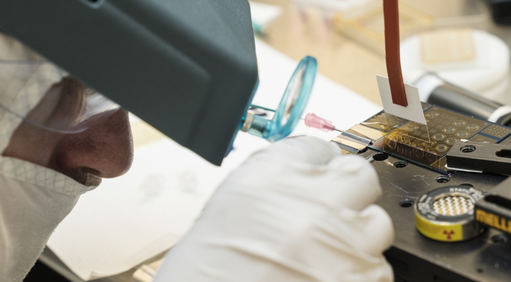 Jakub Kedzierski aligns the polyimide layer, yellow and translucent, on top of the electrode layer. Each small circle and square seen etched in the polyimide is a single actuator, either a rotational or linear actuator respectively. Photo: Glen Cooper