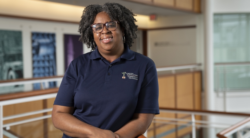 A photo of Chiamaka smiling for a photo, while standing in the lobby of MIT Lincoln Laboratory 