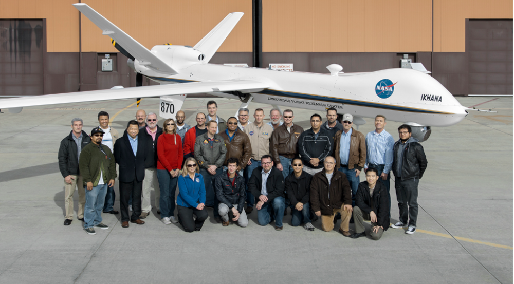 A group of people posing for a photo in front of an aircraft.