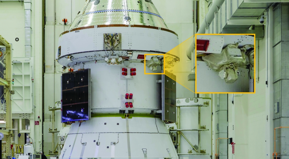 A spacecraft sits inside Kennedy Space Center. A callout box outlines where a laser communications terminal is located on the spacecraft.