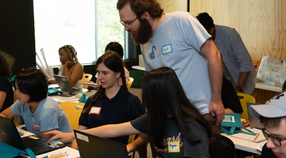 A Lincoln Laboratory staff member assists high school students during the 2024 LLCipher event
