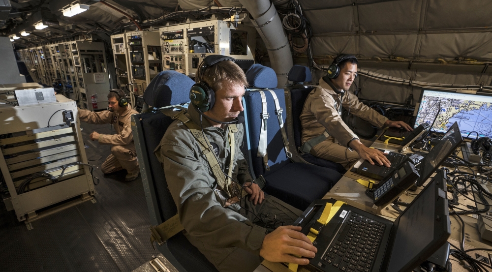Lincoln Laboratory personnel Joseph Zurkus, left, and Jacob Huang, right, operate a protected tactical waveform modem and collect data while Ted O'Connell, back, monitors terminal equipment during flight testing.