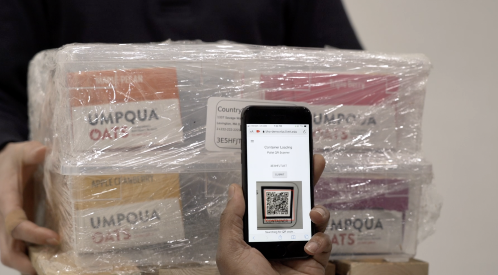a photo of a person scanning a QR code, affixed to a small wrapped shipment of food, with a smartphone.