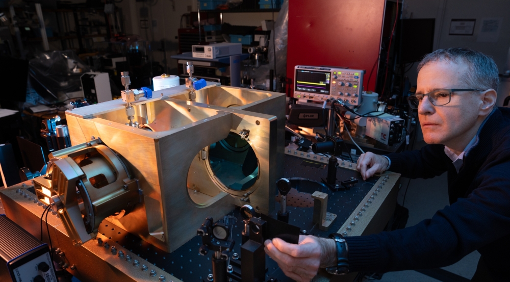 A photo of an interferometer on a lab bench. A staff member is adjusting a part of it.