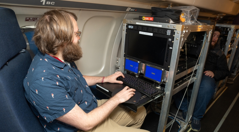 A man types on a keyboard onboard an aircraft.