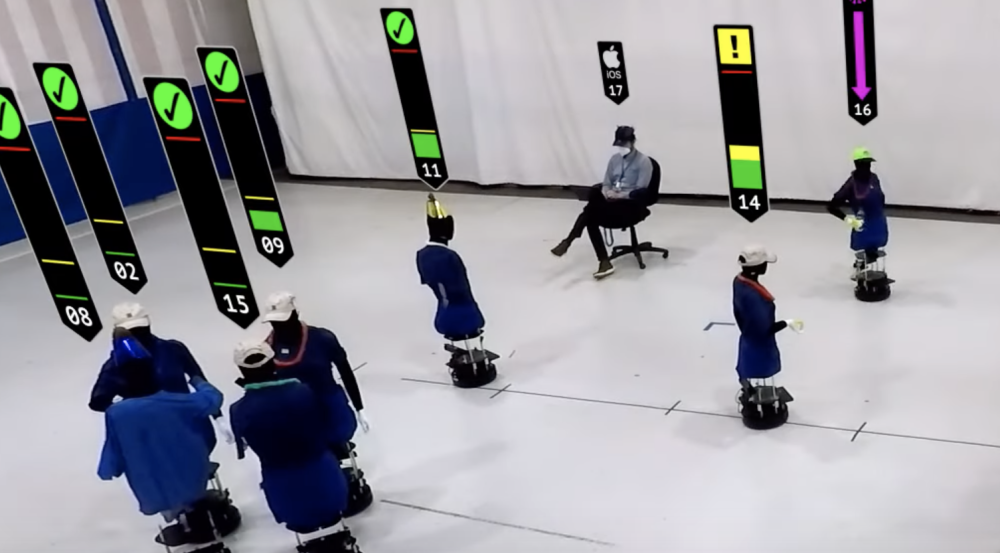 An screengrab from the video showing about a dozen robots in a large room (representing humans at a party) 