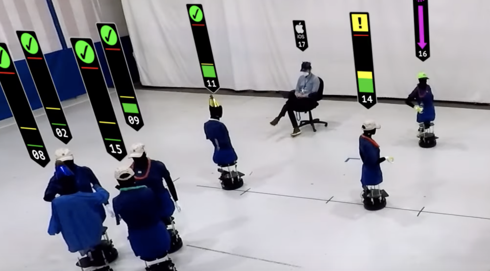 An screengrab from the video showing about a dozen robots in a large room (representing humans at a party)
