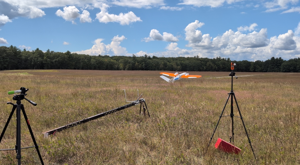 A small drone aircraft is shown launching into a field.